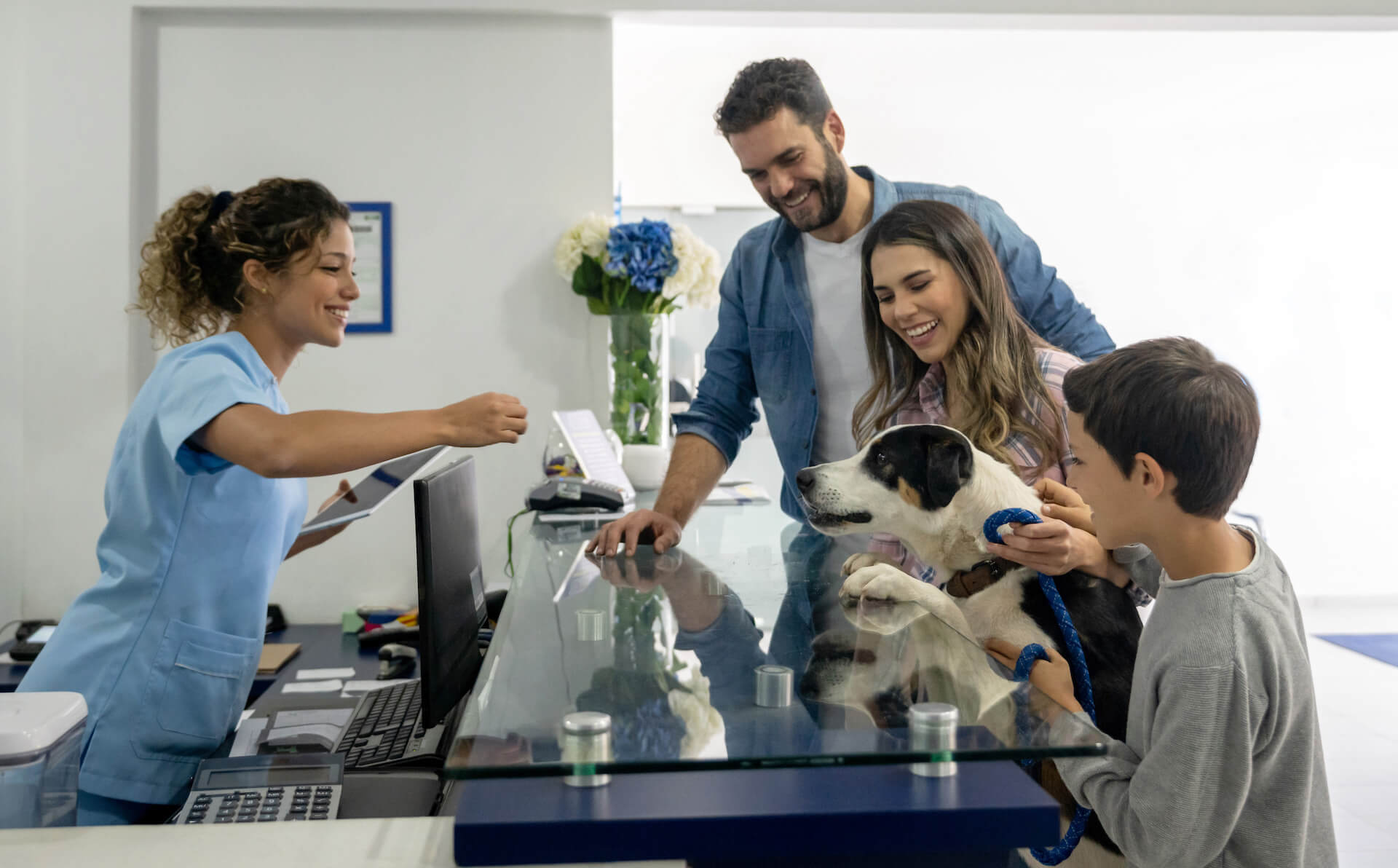 Family with dog at front desk of veterinarian clinic