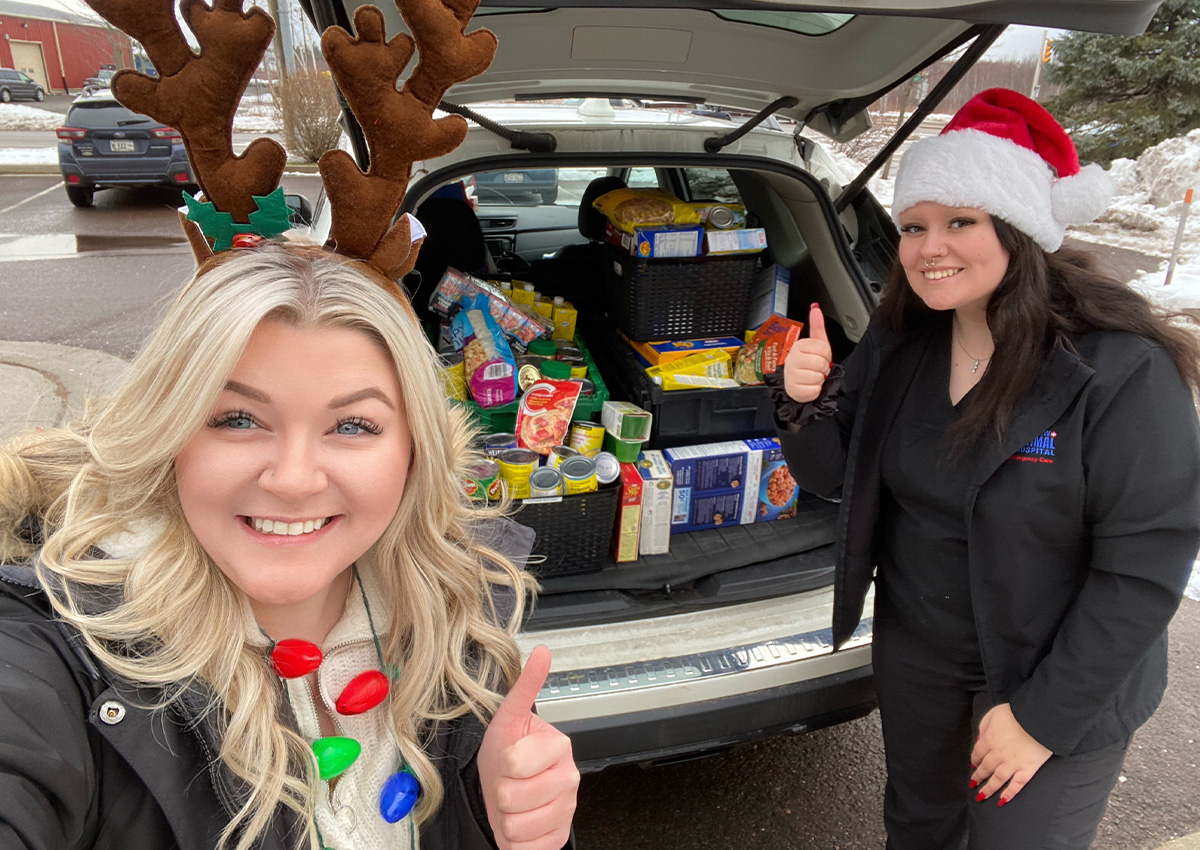 Two people smiling next to car full of donations