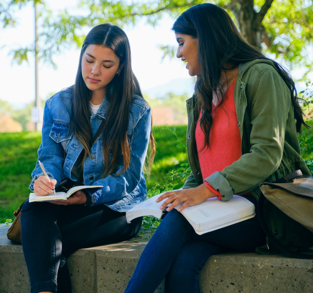 Two people sitting down and taking notes